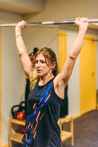 Sportswoman doing press exercise with bar in the gym. Concept of exercises with equipment in gym.