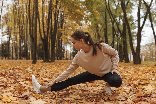 sportswoman doing side lunge exercise and stretching legs while training in autumn park