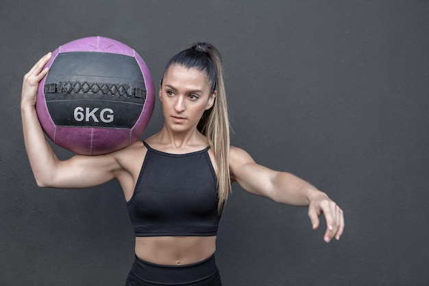 Sportswoman exercising with ball on shoulder