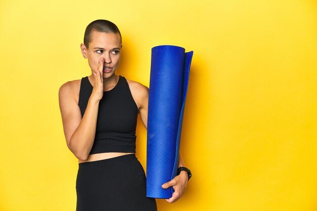 Sportswoman holding yoga mat is saying a secret hot braking news and looking aside