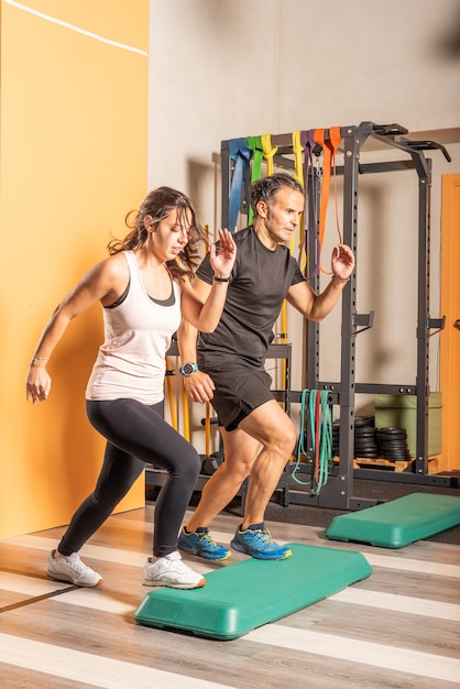 Sportswoman and man doing step up jumps in health club. Concept of exercises with equipment in health club.