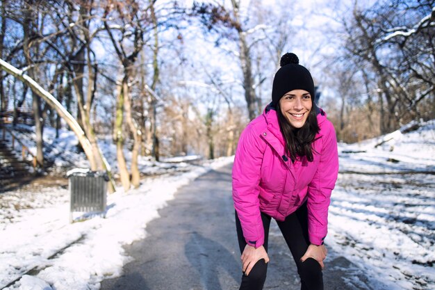 Sportswoman running in the park during the snow and winter.