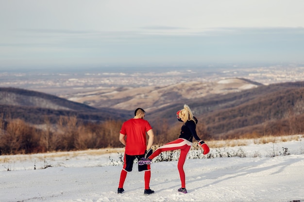 Sportswoman sparring with boxing gloves in nature at snowy winter day with her coach