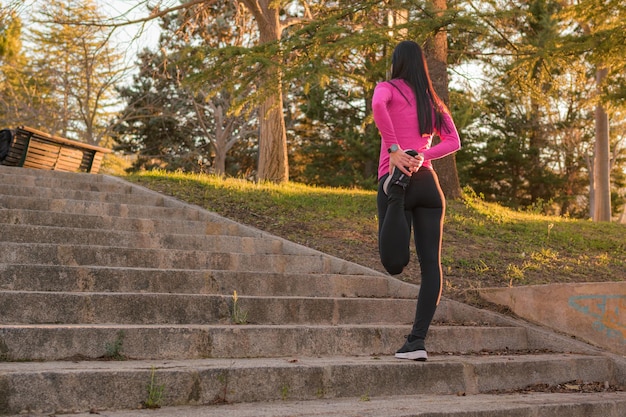 Sportswoman stretching in a park at sunset