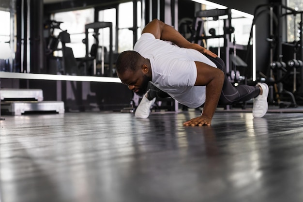 Sporty african man doing pushup in a gym