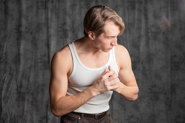 A sporty and athletic guy in a white tshirt boxing a young man in a vintage outfit posing in a studi