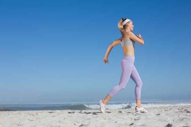 Sporty blonde on the beach jogging