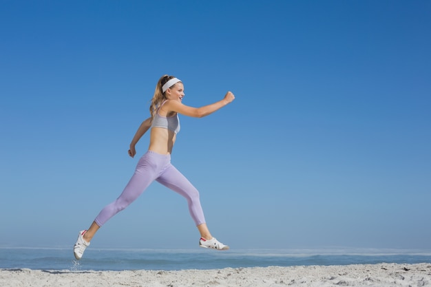 Sporty blonde leaping on the beach