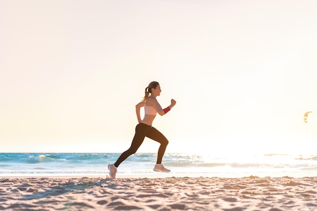 Sporty blonde woman running ocean beach Young caucasian female exercising outdoors running seashore Concept of healthy running and outdoors exercise