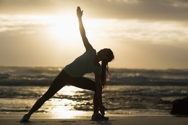 Sporty brunette stretching on the beach 