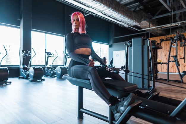 Sporty fashionable young woman in black sportswear working out and exercising in the gym