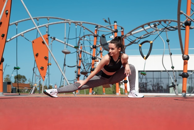 A sporty girl does fitness on a sports field in the summer outdoors