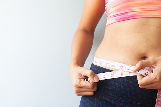 Sporty girl measuring her waist, Reducing excess weight