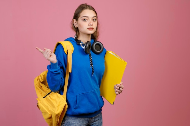 Sporty girl standing holding yellow folder and rucksack