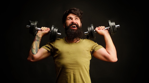 Sporty handsome man lifting dumbbells at gym strong athletic guy strength and motivation fitness