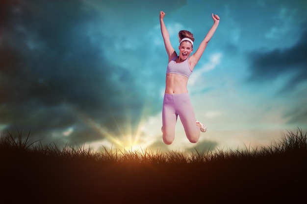 Sporty happy blonde jumping  against blue sky over grass