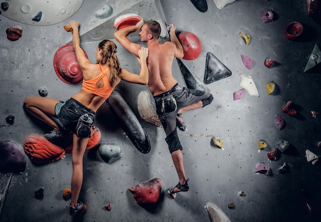 Sporty male and female climbing on an indoor climbing wall.