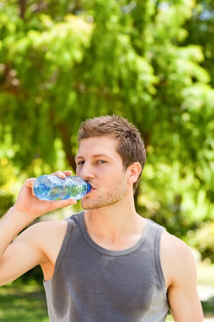 Sporty man drinking water in the park