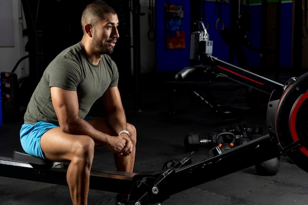 Sporty man watching the board of a rower in the gym