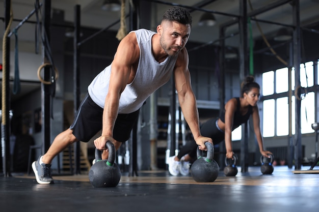 Sporty man and woman doing push-up in a gym.