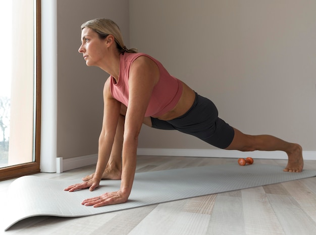 Sporty mature woman with pink tank top doing workout exercises