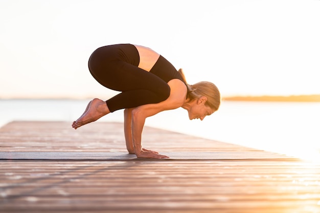 Sporty Middle Aged Female Standing In Crow Pose While Practicing Yoga Outdoors