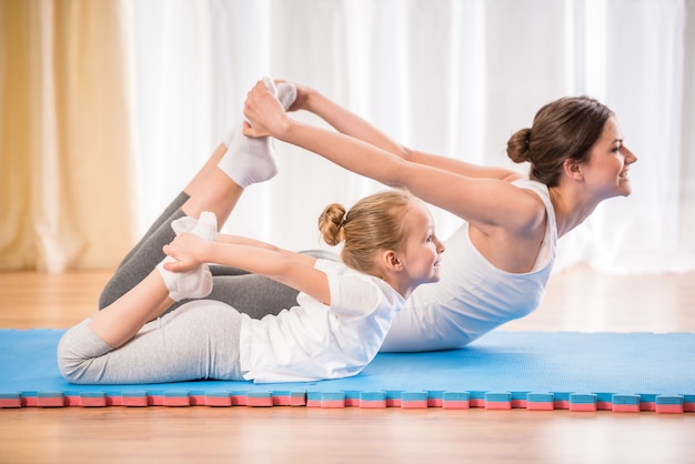 Sporty mother and daughter doing yoga exercises.