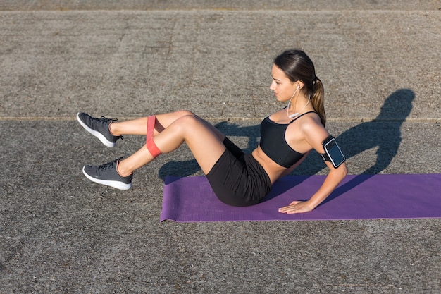 A sporty slim girl in leggings and a top resting between exercises.