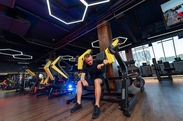 Sporty strong guy with motivation doing exercises Young handsome man training in modern gym