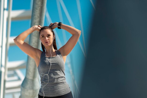 Photo sporty woman athlete tying up hair before a run