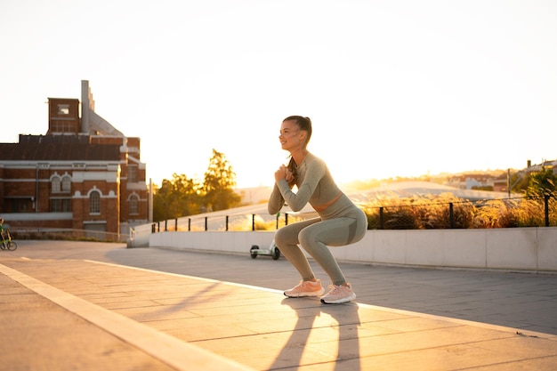 Sporty woman doing jumping squats exercises on stairs in park Bodyweight training on sunset