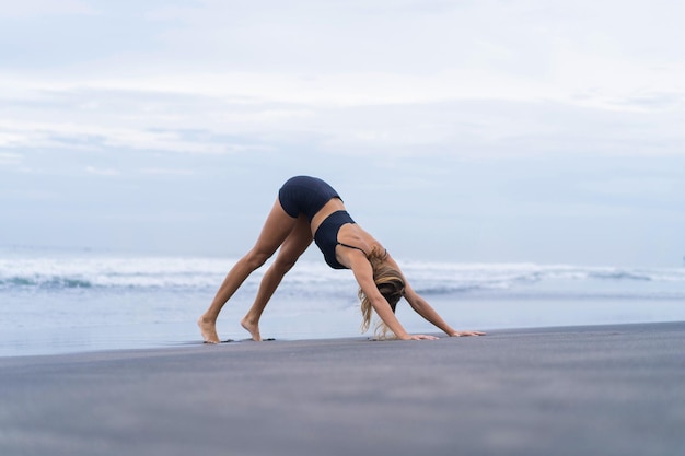 Sporty woman doing mountain climber exercise - run in plank to burn fat. Sunset beach, blue sky background. Healthy lifestyle at tropical island yoga retreat, outdoor activity, family summer vacation.