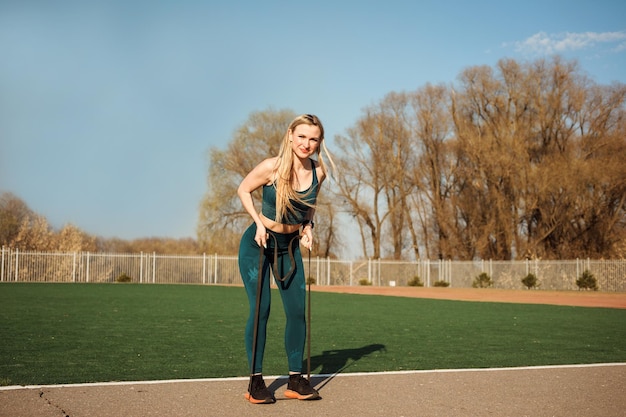 Sporty woman exercising with resistance band on the stadium in spring