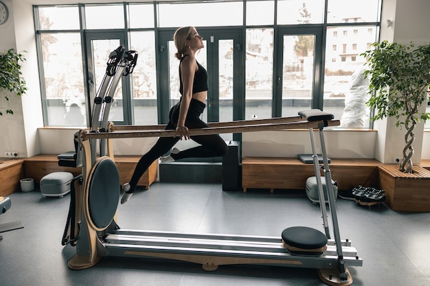 Sporty woman is doing stretching exercises in modern studio