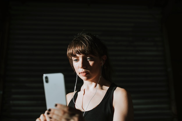 Photo sporty woman listening to music in a dark alley