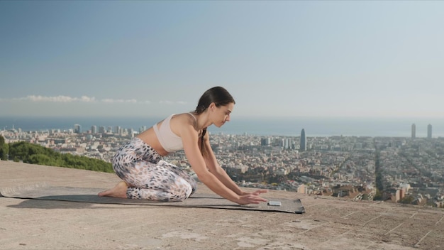 Sporty woman looking video lesson on smartphone during yoga workout outdoors