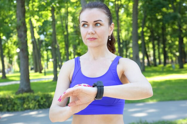 Sporty woman looks at the clock on his hand