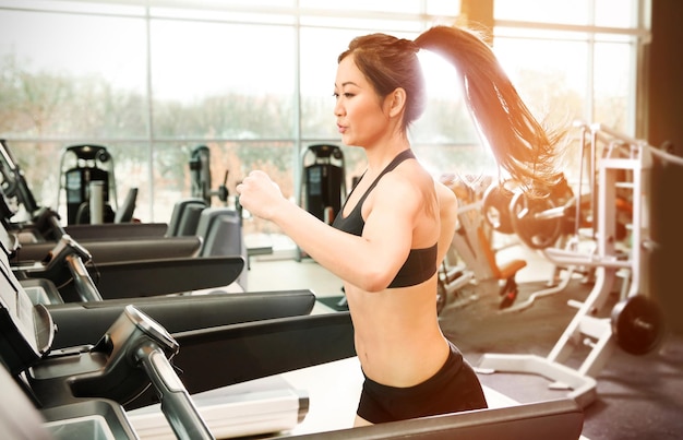 Sporty woman running on treadmill at gym