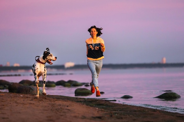 Sporty woman running with dogs on sandy beach