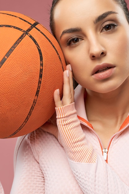 Sporty young woman holding orange basketball ball