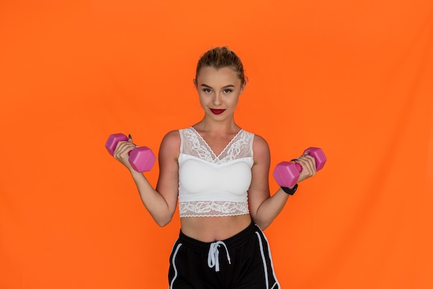 Sporty young woman working out with dumbbells isolated on plain background Sporty woman concept