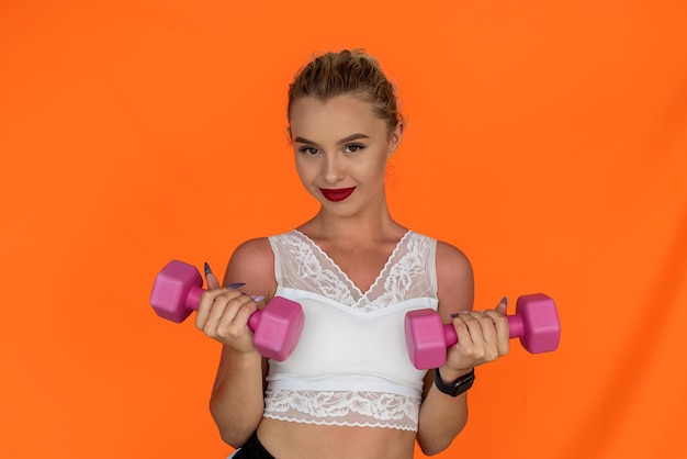 Sporty young woman working out with dumbbells isolated on plain background