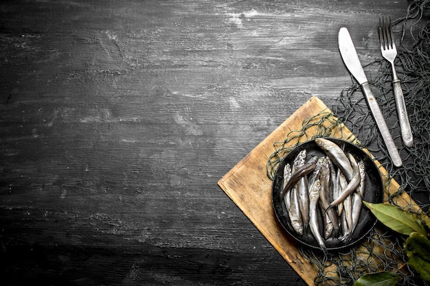 Sprat Bay leaf in a fishing net. On a black wooden background.