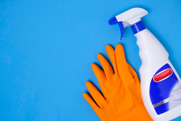 Sprayer for cleaning windows and plumbing and protective rubber gloves blue background