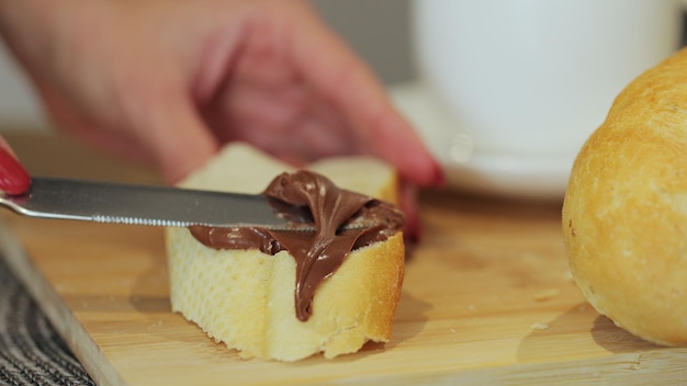 Spread chocolate butter on bread while cooking breakfast making breakfast from wheat bread with bran and chocolate butter