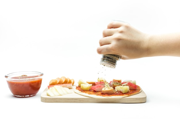 Spreading oregano spices on wooden plate of pizza