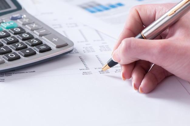 Spreadsheet with hand holding pen and calculator in business stock balance sheet