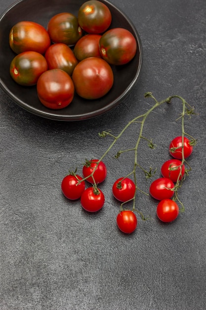 Sprig of cherry tomato red tomatoes in black bowl