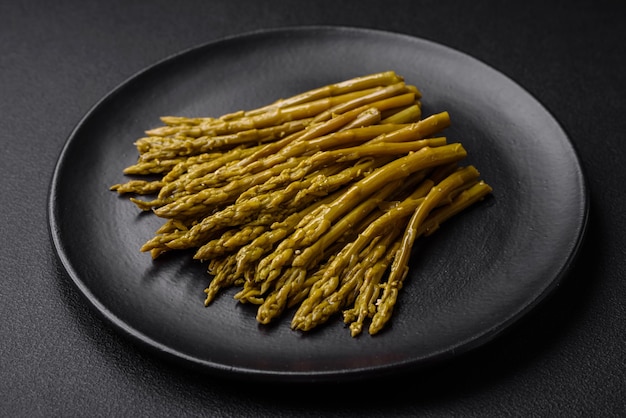 Sprigs of delicious canned asparagus on a black ceramic plate