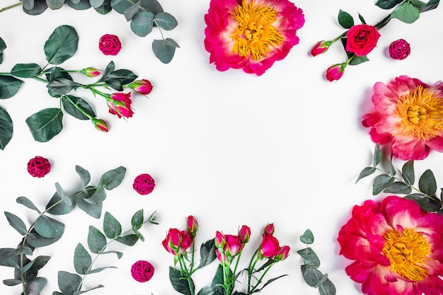 Sprigs of eucalyptus near peonies and roses on white